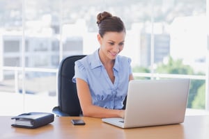 Happy businesswoman working on her laptop in the office